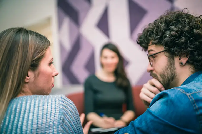 A couple talking to each other, with another person in the background writing notes