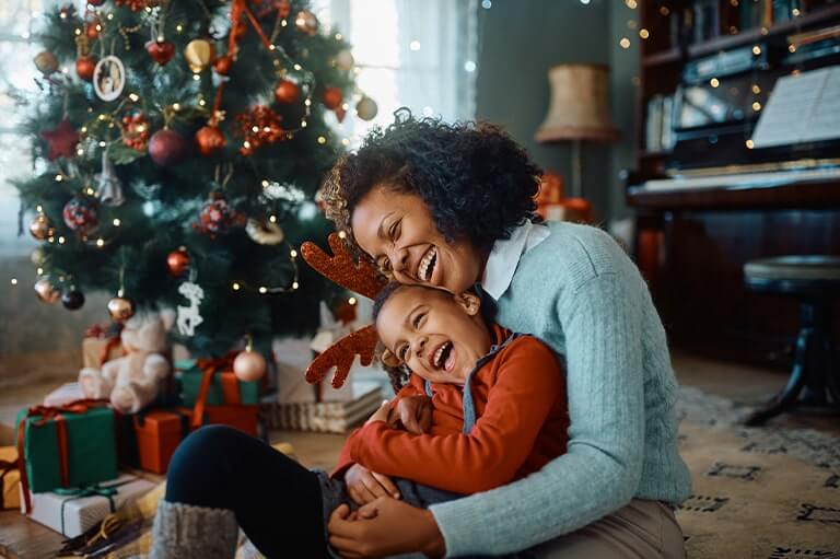 A mum with her child hugging next to a christmas tree